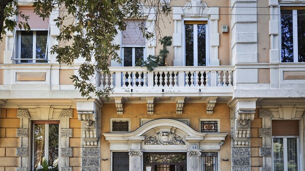 A building with a classic architectural style, featuring a prominent entrance with decorative elements and a balcony above. - Cozy Family Apt in Castelletto by Wonderful Italy (Genova)