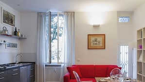 A modern apartment with a kitchen, dining area, and a red sofa. - Cozy Family Apt in Castelletto by Wonderful Italy (Genova)