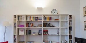 Un espace de travail moderne et fonctionnel, comprenant une bibliothèque, une table à manger avec des chaises transparentes et un téléviseur.