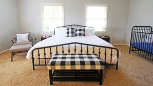 A bedroom with a bed, a bench, a chair, and a crib. - Mountain Views & Solitude. This is Shadow Ridge. Hot Tub. (Fletcher)