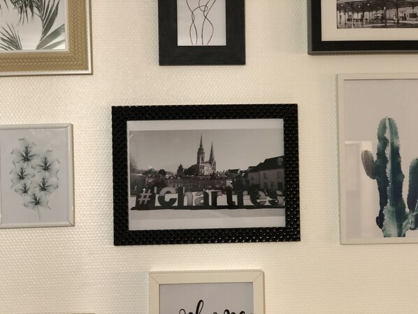 A wall with various framed artworks including floral designs, a cityscape, and a cactus.