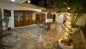 A spacious outdoor area with a tiled floor, wooden doors, and a round table with chairs. - Hotel Boutique La Pergola (Manzanillo)