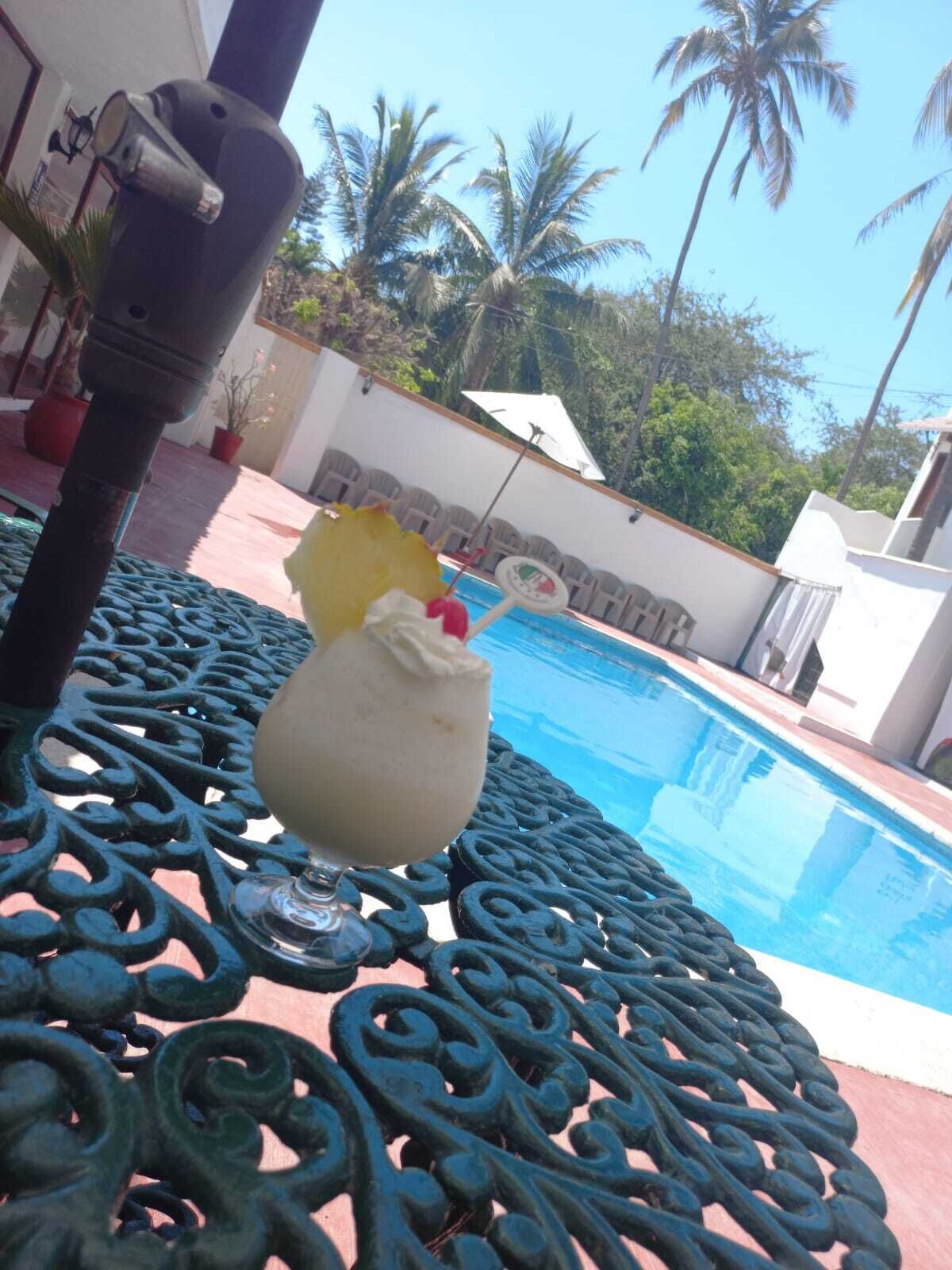 Un cadre agréable au bord de la piscine, avec une table en métal décorative, une boisson servie avec une paille et une piscine à l’eau d’un bleu limpide.