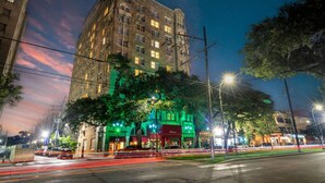 A historic building with a prominent corner entrance, large windows, and a green-lit facade. - Historic Shotgun, Near Streetcar and Superdome (New Orleans)