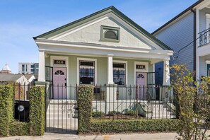 A two-story house with a gabled roof, numbered doors, and a small porch with a railing.