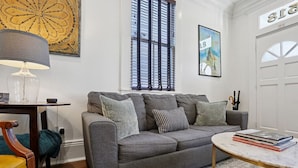A living room with a grey sofa, a round coffee table, a lamp, and a framed picture on the wall. - Historic Shotgun, Near Streetcar and Superdome (New Orleans)
