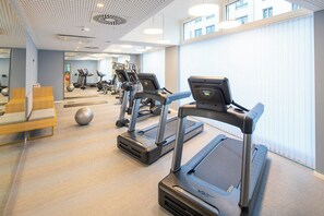 A modern gym with treadmills, exercise balls, and a seating area.