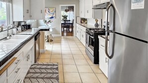 A modern kitchen with white cabinets, stainless steel appliances, and a tiled floor. - Spacious Apt. Min to Downtown Culver City & Venice Beach (Culver City)