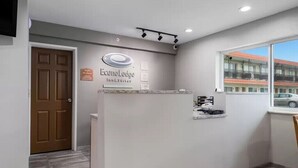 Un espace d’accueil avec une enseigne indiquant « Econo Lodge Inn & Suites », une porte en bois, un comptoir de réception et une fenêtre donnant sur un bâtiment et une voiture.