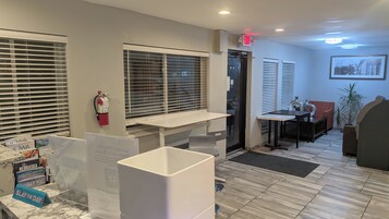 A hotel lobby with a reception desk, seating area, and a fire extinguisher mounted on the wall.