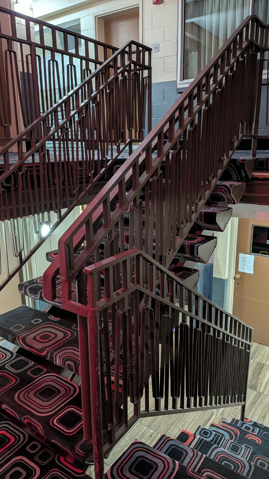 A staircase with a metal railing and patterned carpet.