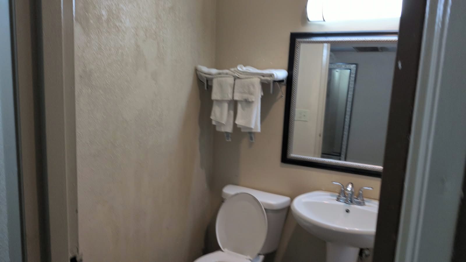 A small bathroom with a toilet, sink, and towel rack.