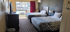 A hotel room with two beds, a desk with a computer, a trash bin, and a window with a view of the outside. - Stay Mason City (Mason City)