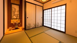 Um quarto japonês tradicional com tatames, portas deslizantes e luminária suspensa.