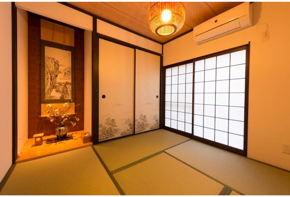 A traditional Japanese room with tatami flooring, sliding doors, and a hanging light fixture.