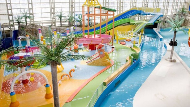 Parque aquático coberto com toboáguas, piscina de ondas e diversas áreas de recreação.