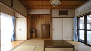 A traditional Japanese room with tatami flooring, a wooden table, sliding doors, and a view through a large window. - Vacation rentals -un- (Nachikatsuura)