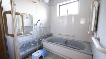 A bathroom with a bathtub, a shower, a toilet, and a window.