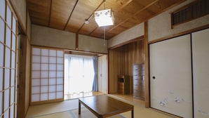 A traditional Japanese room with tatami flooring, a low wooden table, sliding doors, and a ceiling light fixture. - Vacation rentals -un- (Nachikatsuura)
