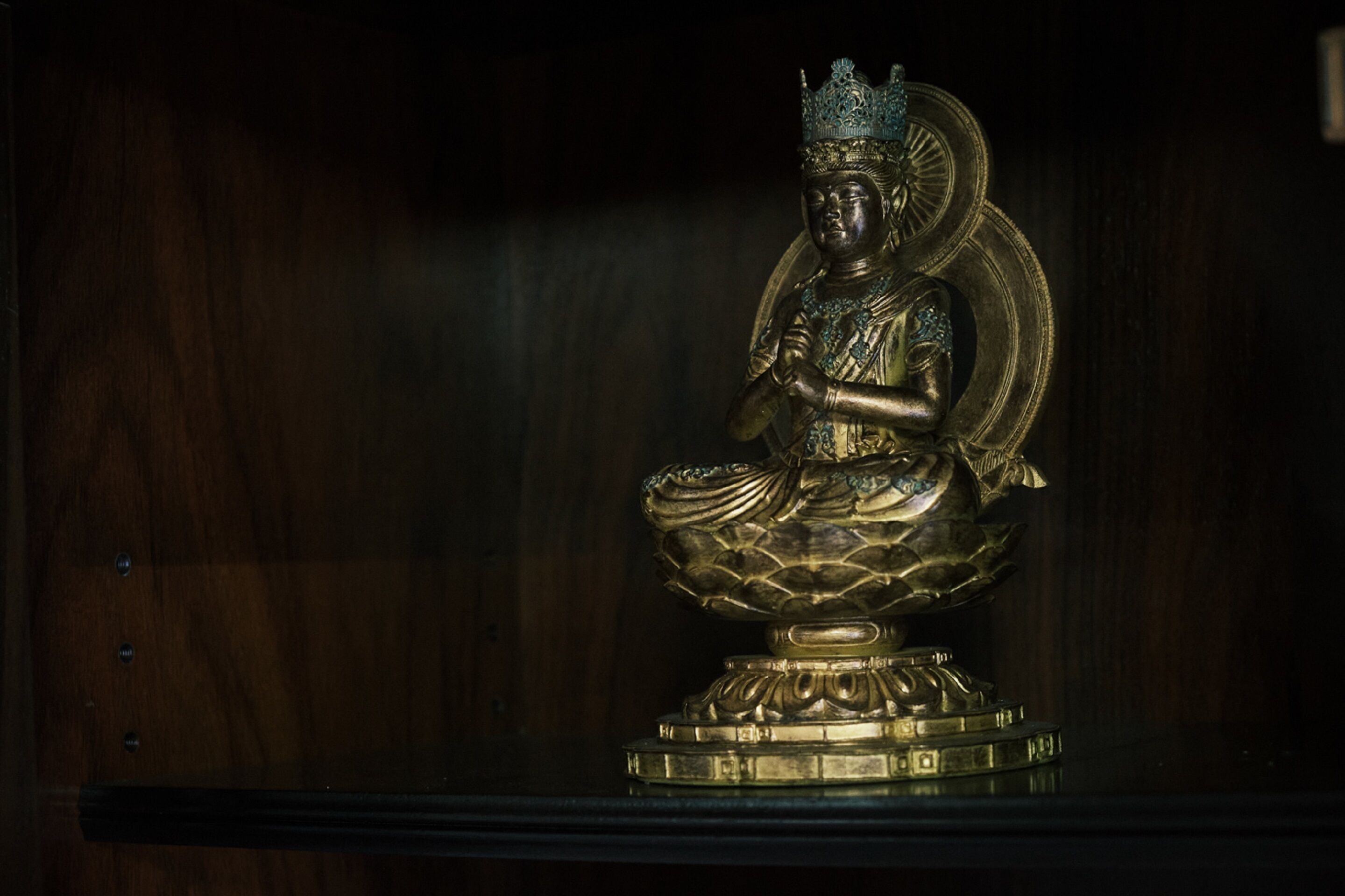 A statue of a seated figure with a crown, placed on a pedestal.
