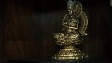 A statue of a seated figure with a crown, placed on a pedestal.