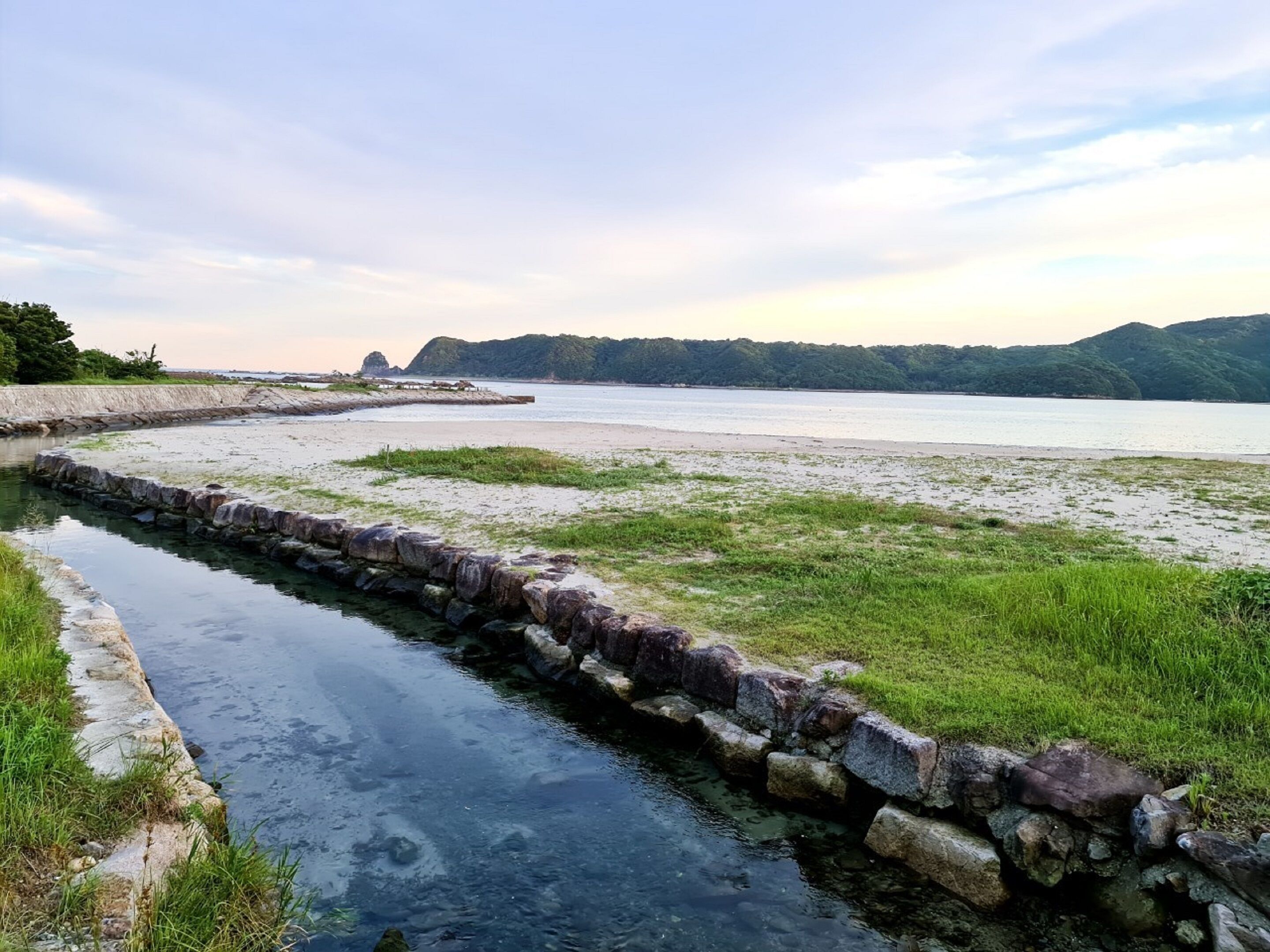 A river with a stone embankment and grassy banks.