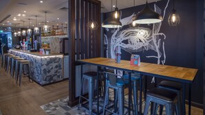 Eine Bar mit Sitzhocker, einer Theke und hängenden Pendelleuchten.