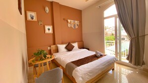 A bedroom with a bed, a small table with a plant, a chair, and a balcony with curtains. - HANZ Chuong Hotel Da Lat (Xuan Huong - Da Lat)