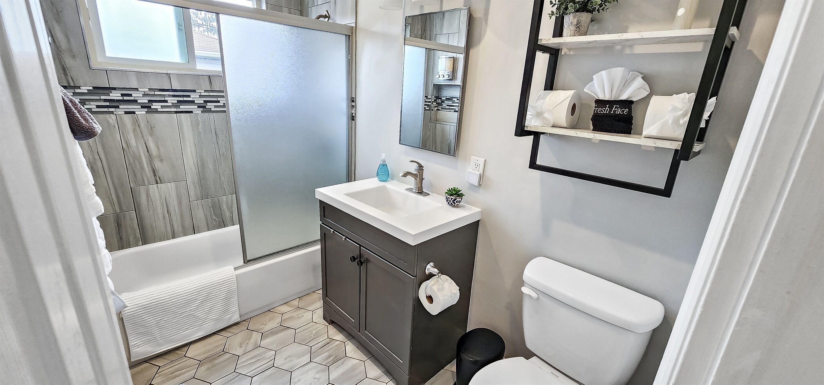 A modern bathroom with a shower, toilet, and sink.