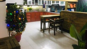 A kitchen with a wooden table and chairs, a Christmas tree, and a tiled floor.