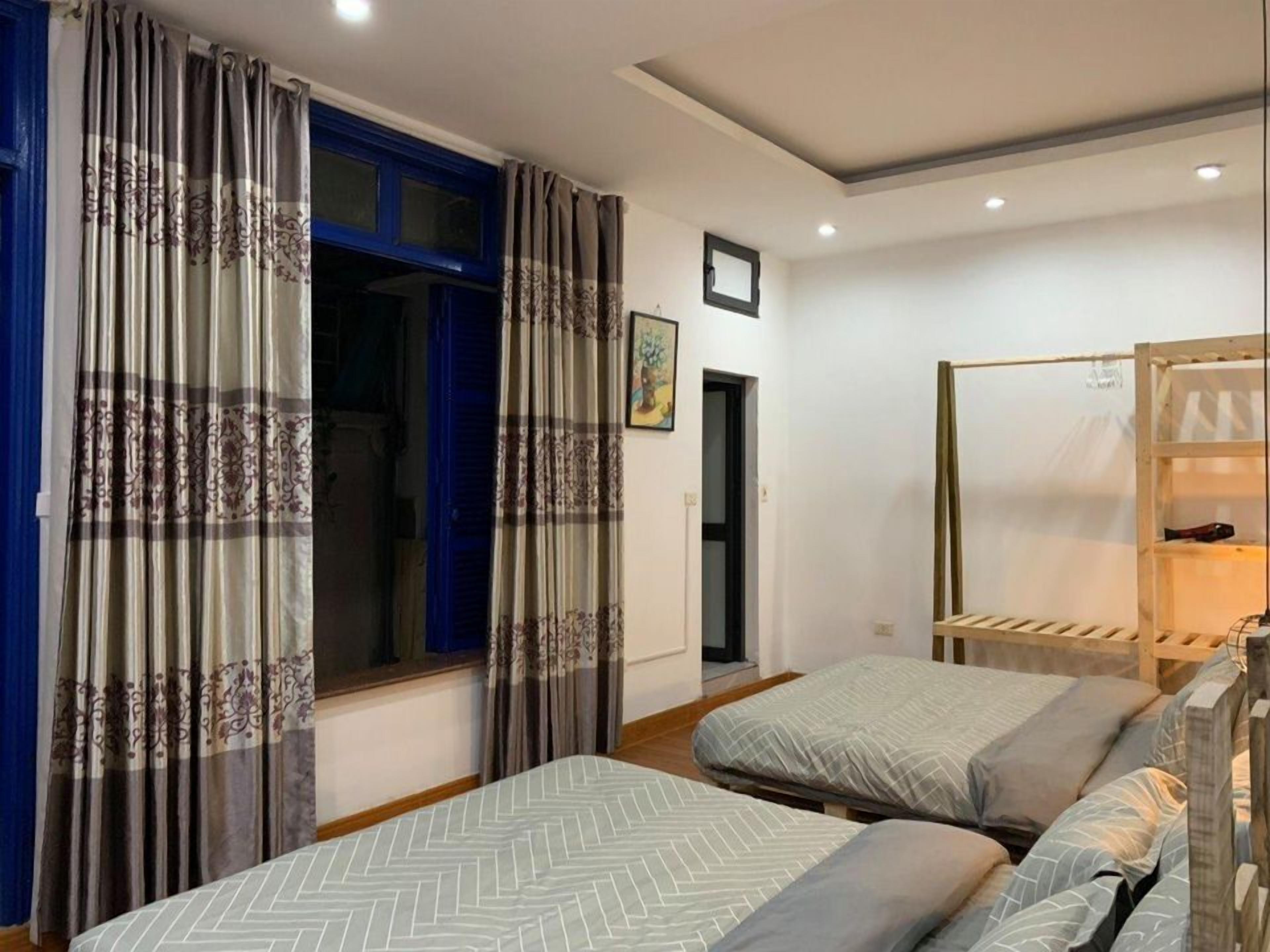 A bedroom with two beds, a wardrobe, and a window with curtains.