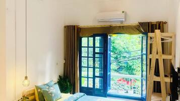 A room with two beds, a ceiling fan, a window with curtains, and a wooden ladder.