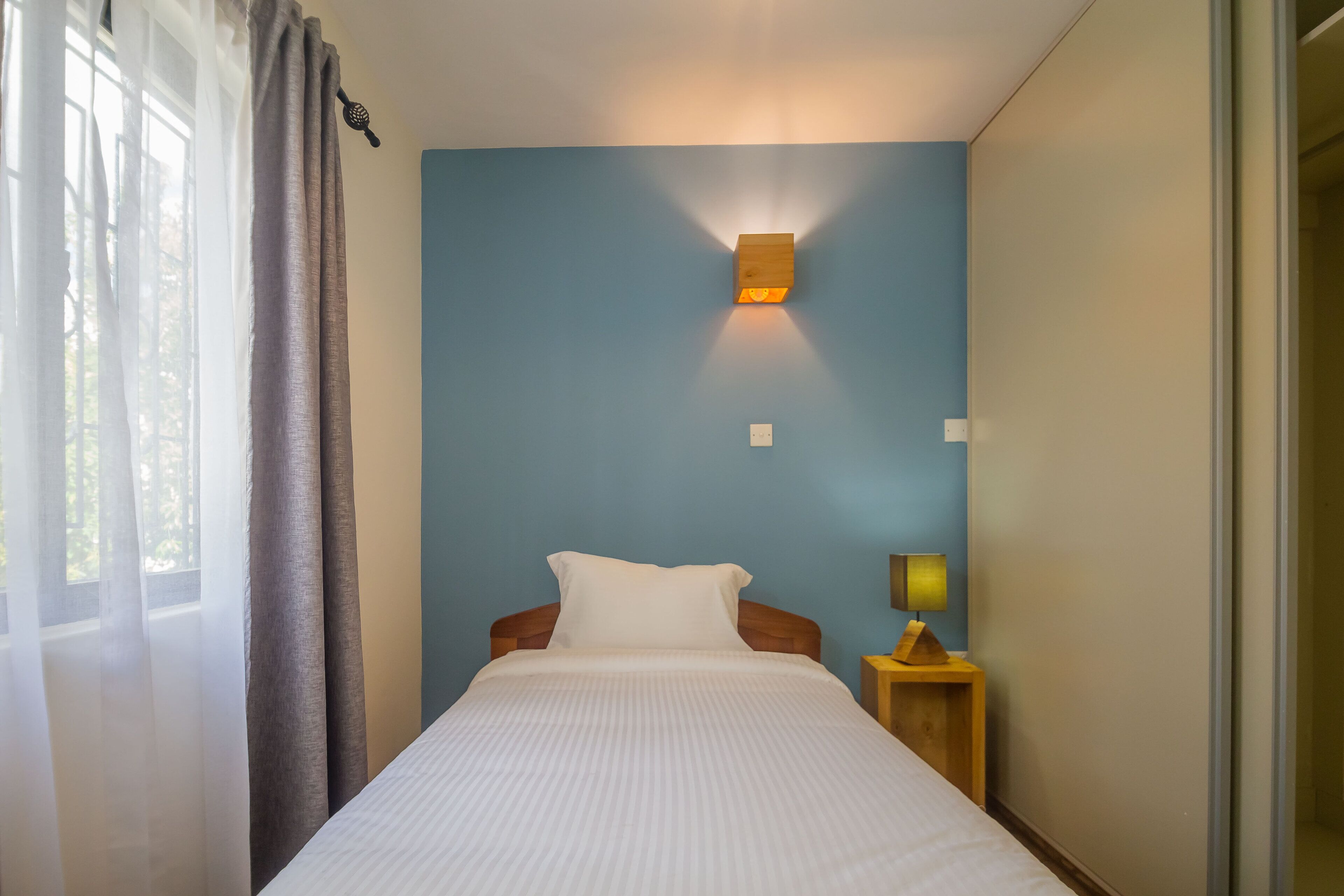 Une chambre à coucher avec un lit, une table de chevet avec une lampe et un luminaire fixé au mur.