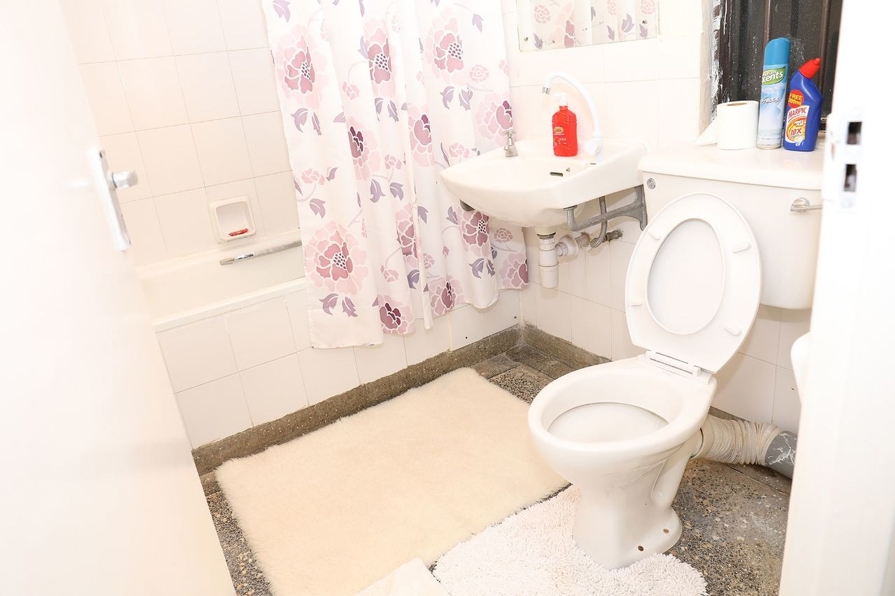 A bathroom with a toilet, sink, and shower curtain.