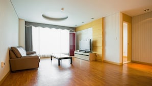 A spacious living room with a wooden floor, a sofa, a coffee table, and a television. - Seaspovill Resort (Samcheok)
