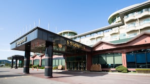 A modern hotel with a prominent entrance, large windows, and a distinctive curved balcony structure. - Seaspovill Resort (Samcheok)