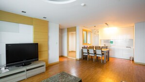 A modern living room with a flat-screen TV, a bench, and a dining area with chairs and a table. - Seaspovill Resort (Samcheok)