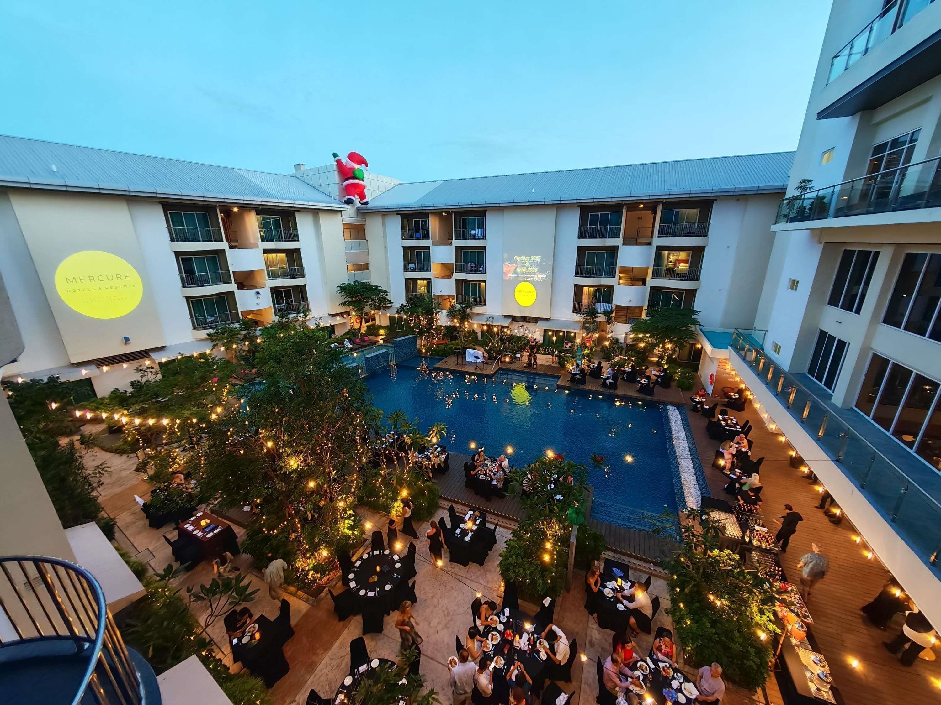 Un hotel con piscina central, comedor al aire libre y decoración navideña.