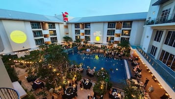 Un hotel con piscina central, comedor al aire libre y decoración navideña.
