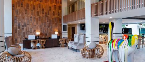 A spacious lobby with a reception desk, seating area, and a colorful elephant sculpture.
