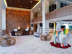 A spacious lobby with a reception desk, seating area, and a colorful elephant sculpture.