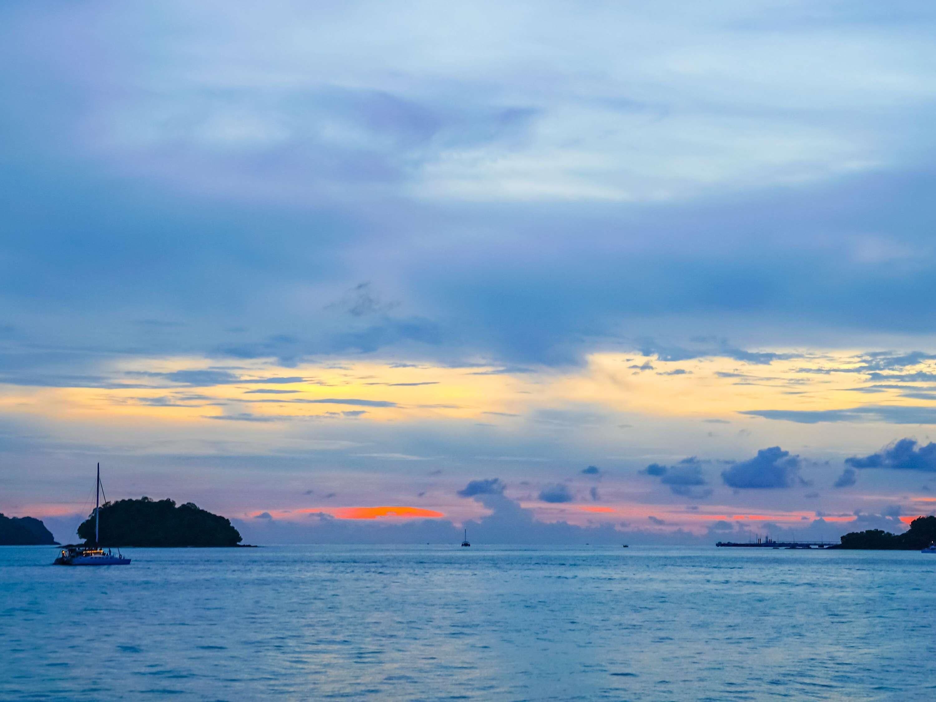 Ein ruhiges Meer mit einer fernen Insel und einem Sonnenuntergang.
