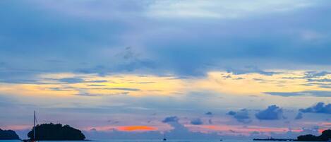 Ein ruhiges Meer mit einer fernen Insel und einem Sonnenuntergang.