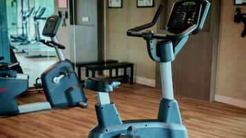 Una máquina elíptica LifeCycle en un gimnasio con suelo de madera, otros equipos de ejercicio y un espejo en la pared.