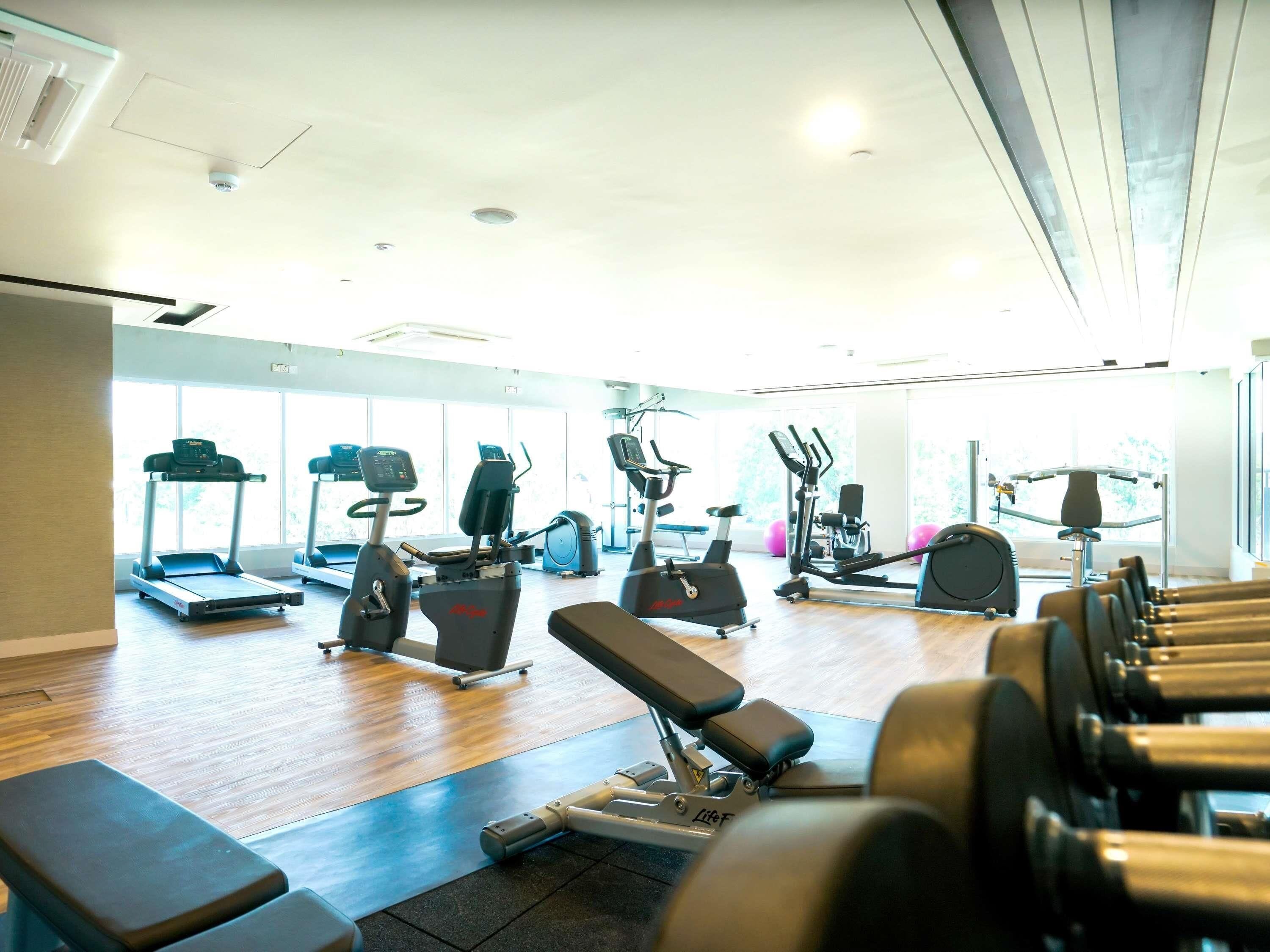 Une salle de sport équipée de tapis de course, de vélos elliptiques et de bancs de musculation.