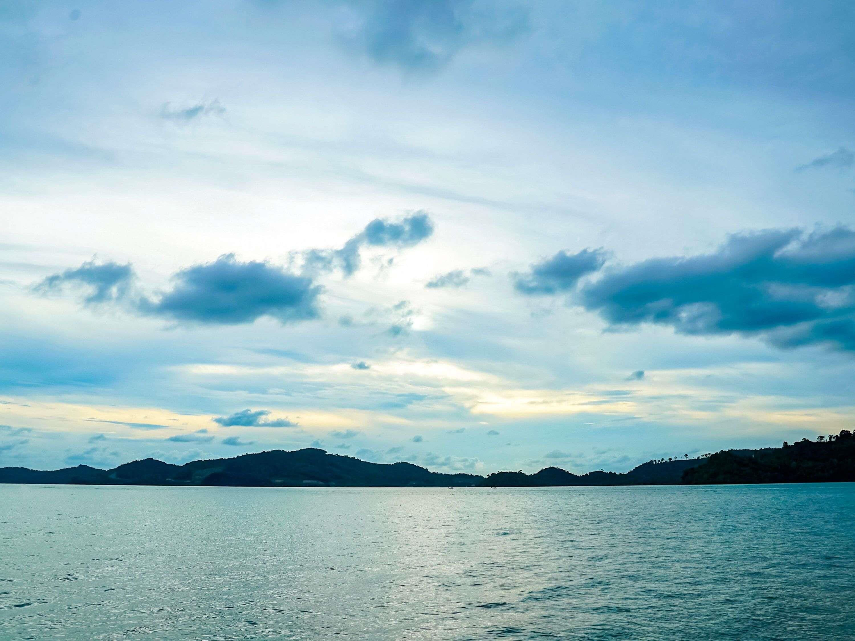 A calm body of water with distant landforms and a cloudy sky.