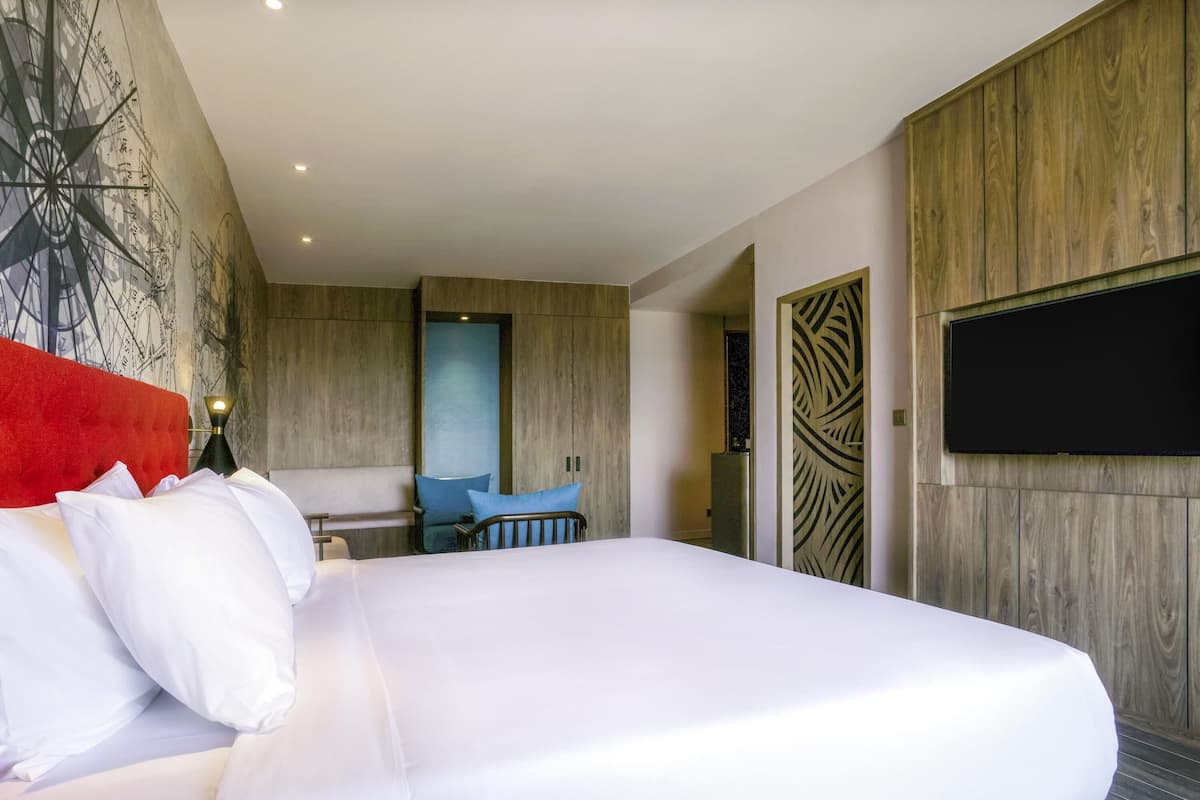 Een hotelkamer met een groot bed, een bureau, een televisie en een muur met een ontwerp van een kompas.