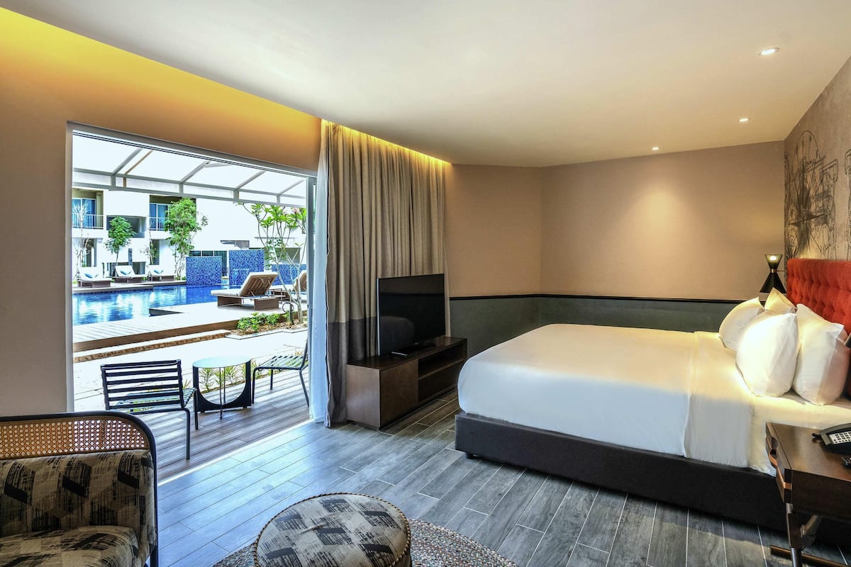 Hotelkamer met een bed, televisie en uitzicht op een buitenzwembad.