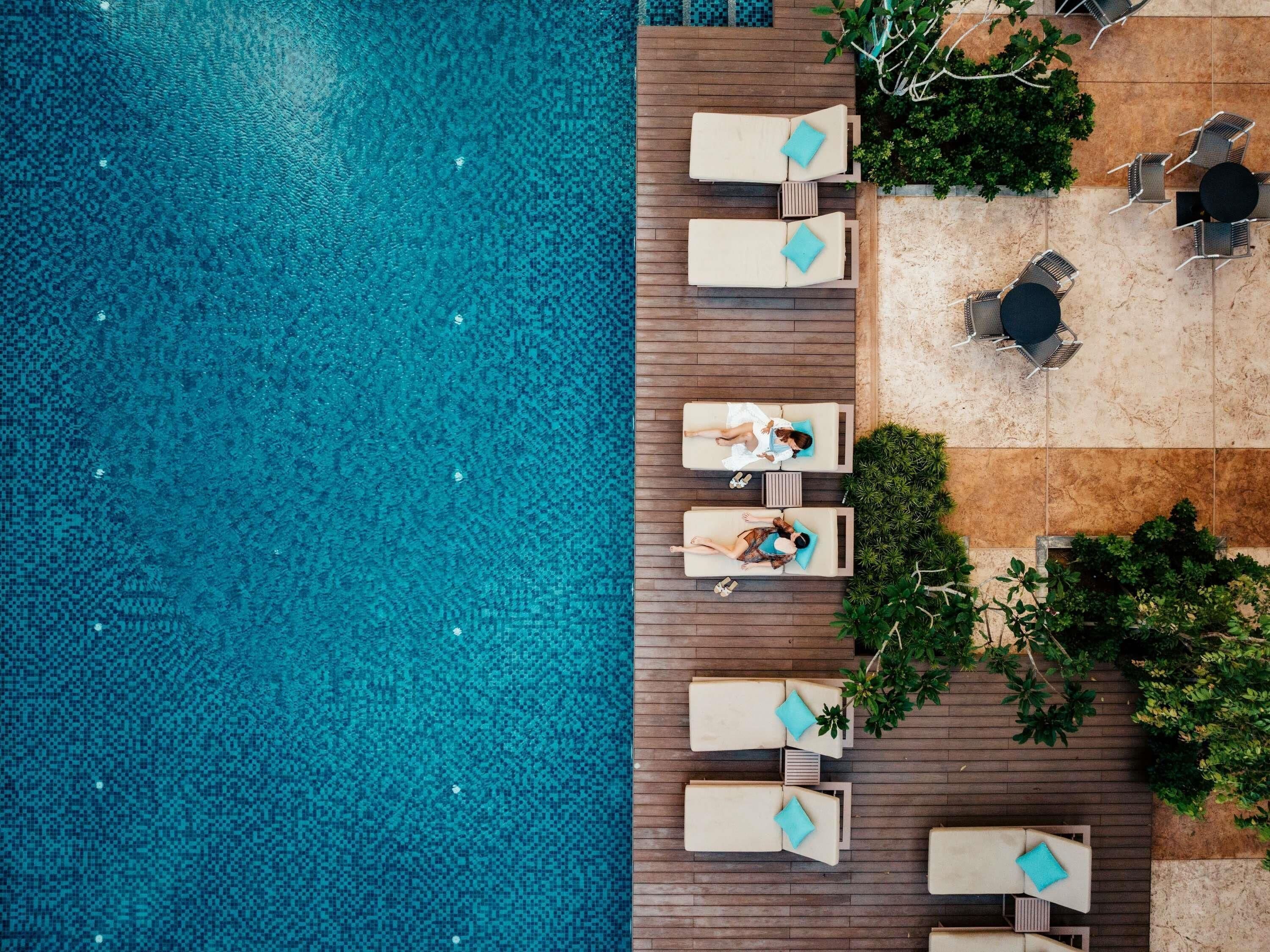An aerial view of a poolside area with lounge chairs and a small table.