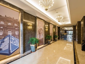 A long, polished hallway with marble floors, large potted plants, and wall murals. - Mercure Changzhou Jintan (Changzhou)